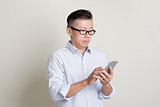 Portrait of mature Asian man using smartphone