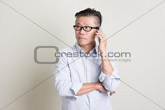 Mature Asian man calling on smartphone