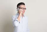 Mature Asian man making call on smartphone