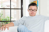 Mature 50s Asian man sitting at home.