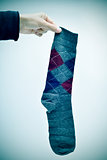 man holding an argyle patterned sock, vignetted