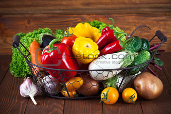 Fresh vegetables in basket on wooden board