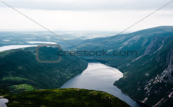 Inland fjord between steep cliffs against green landscape