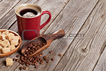 Coffee cup, beans and brown sugar on wooden table