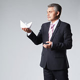 Portrait of businessman holding paper boat.