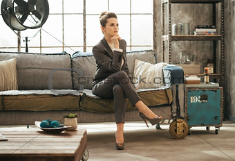Elegant brunet business woman is sitting on couch in loft