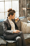 Business woman sitting on sofa and drinking coffee in loft