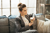 Young businesswoman is sitting on couch with cup of coffee