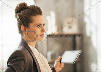 Concentrated businesswoman holding tablet in loft apartment