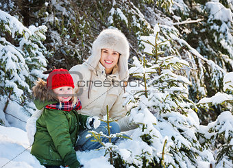 Happy mother and child outdoors among snowy spruces