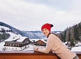 Smiling woman on balcony overlooking the snow-capped mountains
