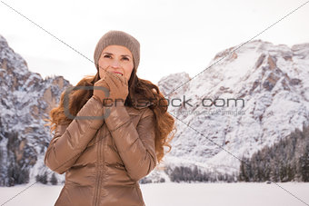 Woman warming hands outdoors among snow-capped mountains