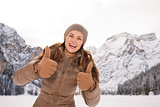 Woman showing thumbs up outdoors among snow-capped mountains