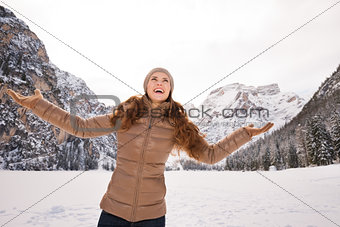Woman catching snowflakes outdoors among snow-capped mountains