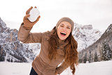 Woman outdoors among snow-capped mountains throwing snowball