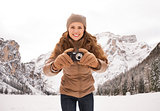 Woman with compact camera outdoors among snow-capped mountains