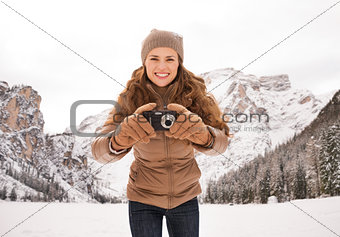 Woman with compact camera outdoors among snow-capped mountains