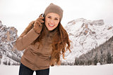 Woman talking cell phone outdoors among snow-capped mountains