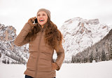 Woman talking cell phone outdoors among snow-capped mountains