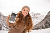 Woman outdoors among snow-capped mountains showing cell phone