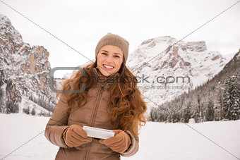 Woman outdoors among snow-capped mountains writing sms