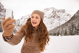 Young woman taking selfie outdoors among snow-capped mountains
