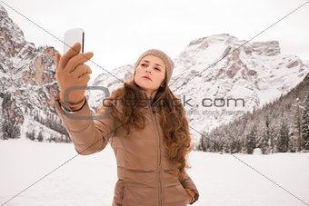 Woman taking selfie outdoors among snow-capped mountains