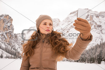 Woman taking photo outdoors among snow-capped mountains