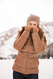 Woman hiding behind collar outdoors among snow-capped mountains