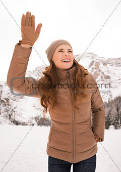 Happy woman outdoors among snow-capped mountains calling someone