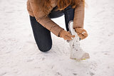 Closeup on woman tying shoelaces in gloves outdoors