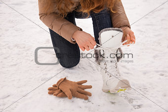 Closeup on woman tying shoelaces without gloves outdoors