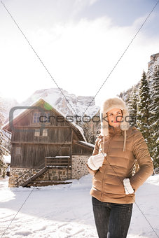 Woman looking aside while standing in front of mountain house