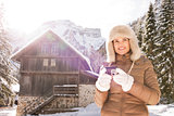 Woman holding digital camera while standing near mountain house