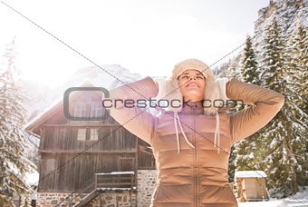 Relaxed young woman standing in the front of cosy mountain house
