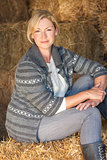 Middle Aged Blond Woman Sitting on Hay Bale