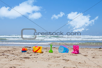 Colorful plastic beach toys lying on the beach sand