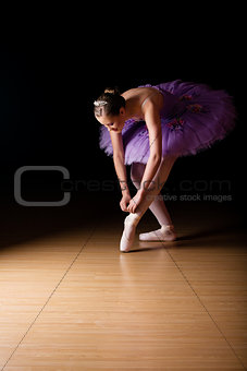 Young female ballerina adjusting her shoes