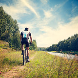 Man Riding a Bicycle on River Bank