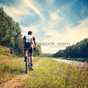 Man Riding a Bicycle on River Bank