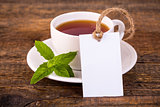 Cup of tea with green leaves and blank tag