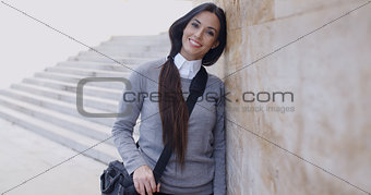Grinning woman in sweater near wall looking over