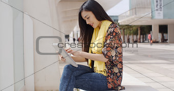 Young woman sitting reading her tablet
