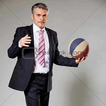 Business man playing with a basketball at the studio
