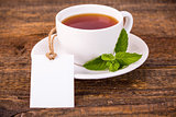Cup of tea with green leaves and white tag