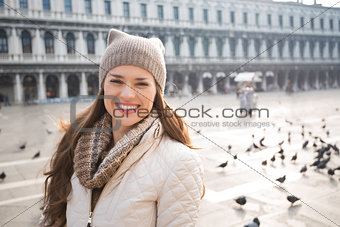 Portrait of happy young woman on Piazza San Marco among pigeons