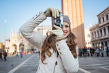 Woman taking photos with retro photo camera on Piazza San Marco