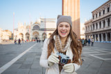 Smiling woman with retro photo camera on Piazza San Marco
