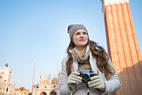 Pensive woman holding camera in front of Campanile di San Marco