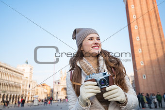 Happy woman holding retro photo camera on Piazza San Marco